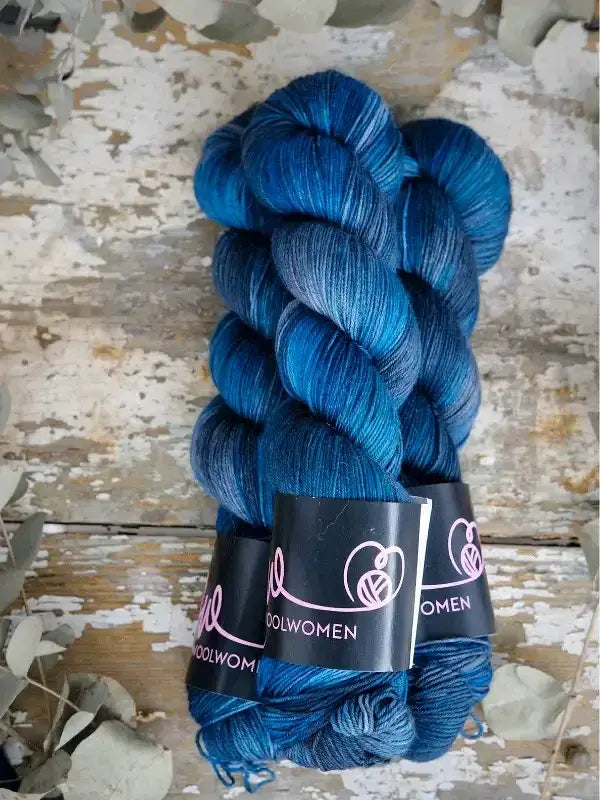 Two twisted skeins of WoolWomen Merino Sock hand-dyed variegated blue merino wool.