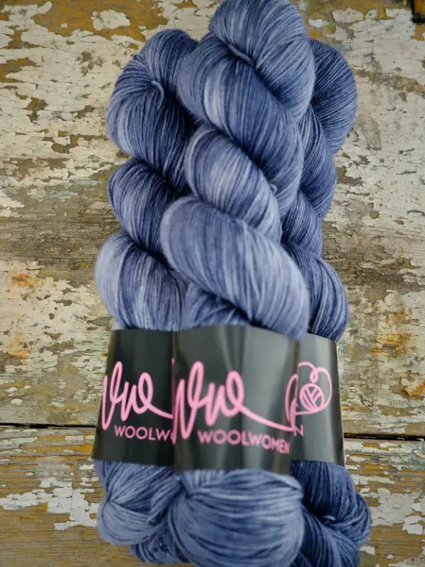 A twisted skein of WoolWomen Merino Sock hand-dyed superwash merino wool in variegated blue and grey.