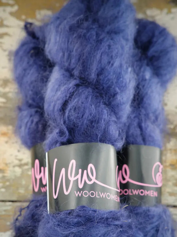 A skein of WoolWomen Fluff Mohair in fuzzy, deep blue with a black paper label.