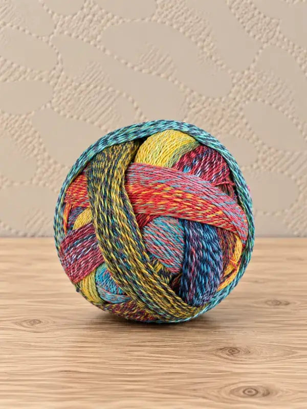 A ball of Schoppel wolle Zauberball crazy yarn with blended tones of blue, yellow, and red superwash-villa.