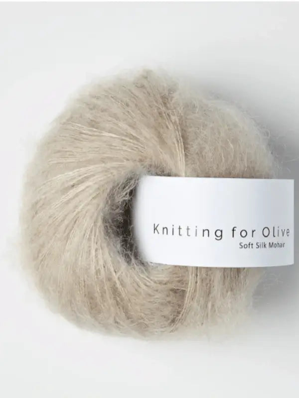 A ball of Knitting for Olive Soft Silk Mohair yarn in light beige, crafted from luxurious kid mohair and silk, with a white label displaying the product name, set against a plain background.