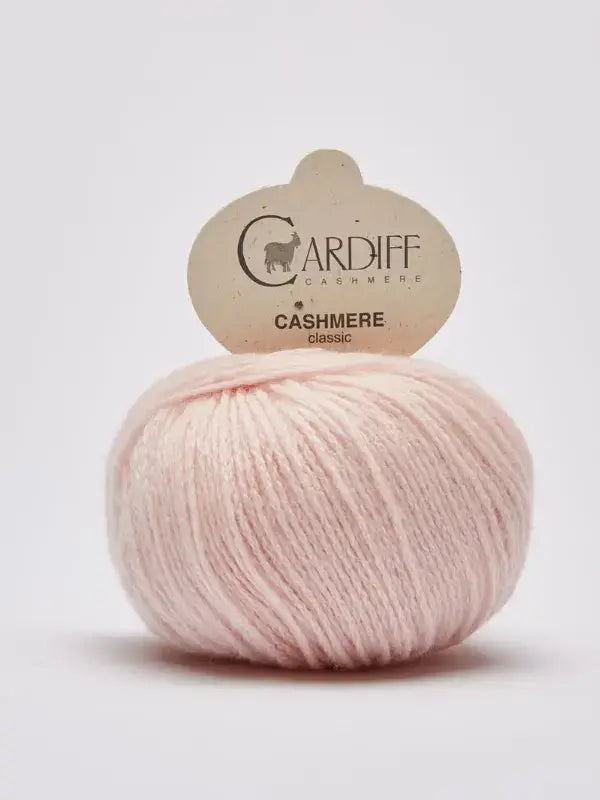 A ball of pale pink Cardiff Cashmere Classic – 100 % kashmirlanka yarn, celebrated for its luxurious Italian cashmere fibers, features a beige label with the brand and logo, set against a plain white background.