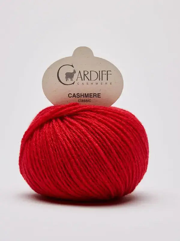 A bright red ball of Cardiff Cashmere Classic – 100 % kashmirlanka, made from luxurious kashmir, sits against a plain white background with its label attached at the top.