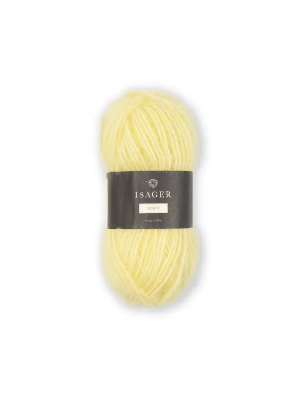 A skein of soft, pale yellow Isager Soft yarn with a black and gray paper band around the center, shown on a plain white background.