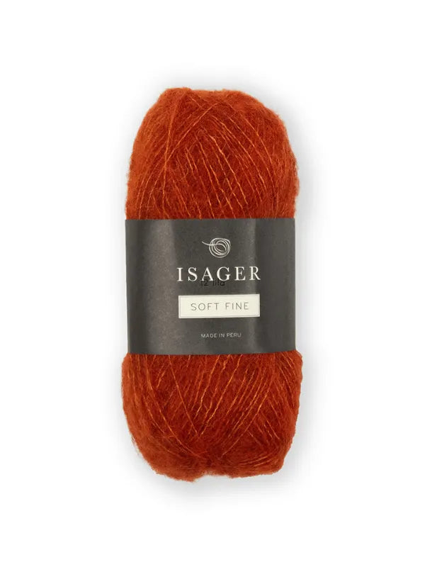 A skein of rust-colored Isager Soft Fine yarn with a dark gray band featuring white text, shown against a plain white background.