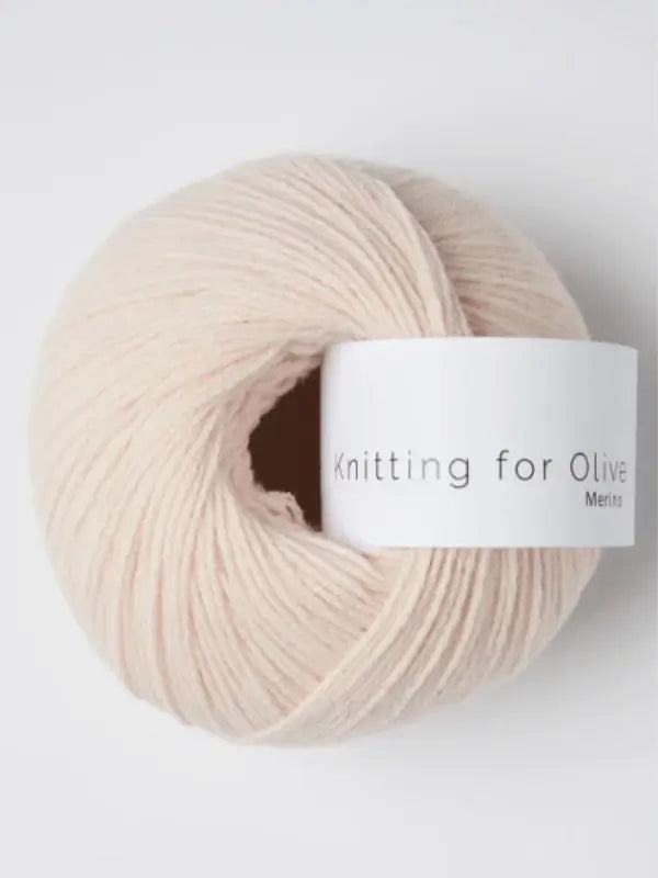 A ball of pale pink Knitting for Olive Merino yarn with a white label in gray text. The yarn is Öko-Tex certified, making it a safe and sustainable choice for your knitting projects.