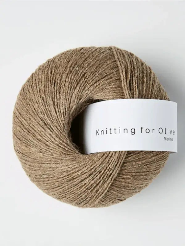 A ball of light brown Knitting for Olive Merino yarn with a white label sits against a plain white background. This merino yarn is also Öko-Tex certified, ensuring it’s safe and gentle for all projects.