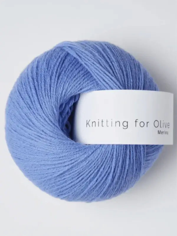A ball of light purple-blue Knitting for Olive Merino yarn with a white label reading "Knitting for Olive"; this merino wool yarn is Öko-Tex certified.