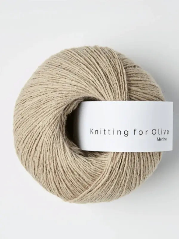 A ball of light beige Knitting for Olive Merino yarn with a white label sits against a plain white background.