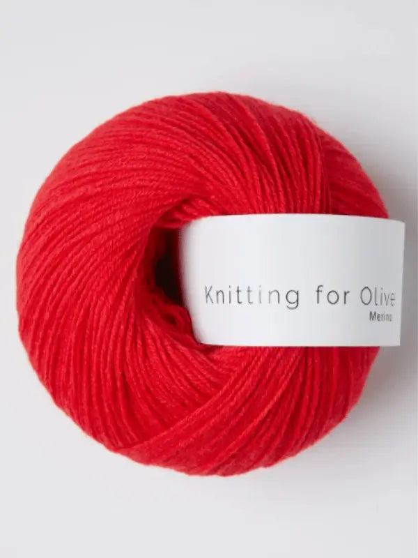 A vibrant red ball of Knitting for Olive Merino yarn with a white label, set against a simple light background.
