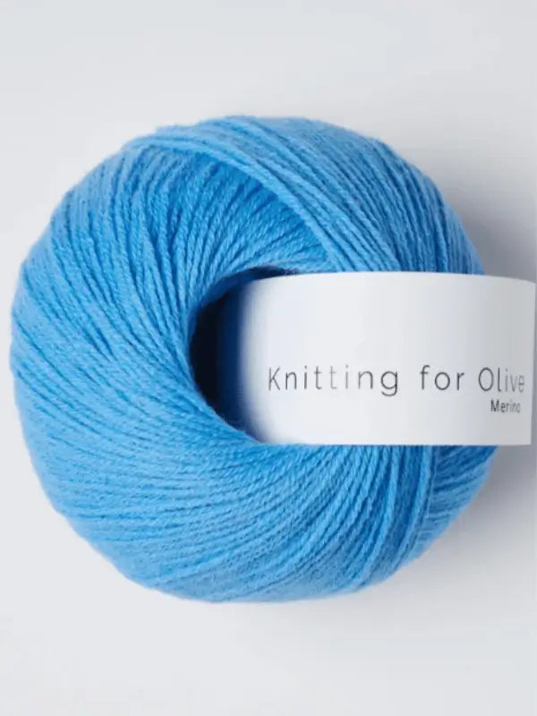 A ball of bright blue Knitting for Olive Merino yarn with a white label sits against a plain white background. The yarn is made from Öko-Tex sertifioitu merinovillalanka.