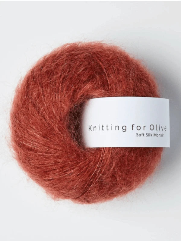 A ball of Knitting for Olive Soft Silk Mohair yarn in a reddish-brown shade, featuring Responsible Mohair Standard kid mohair and silkki lanka, is displayed against a white background.