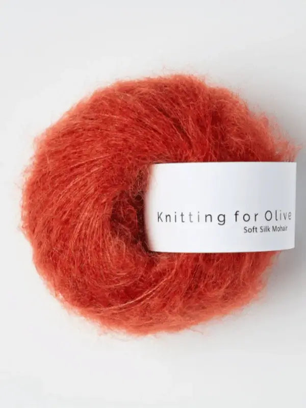A ball of plush, rust-orange Knitting for Olive Soft Silk Mohair yarn with a white label, featuring vastuullinen mohair and crafted from premium silkkimohair, set against a plain background.