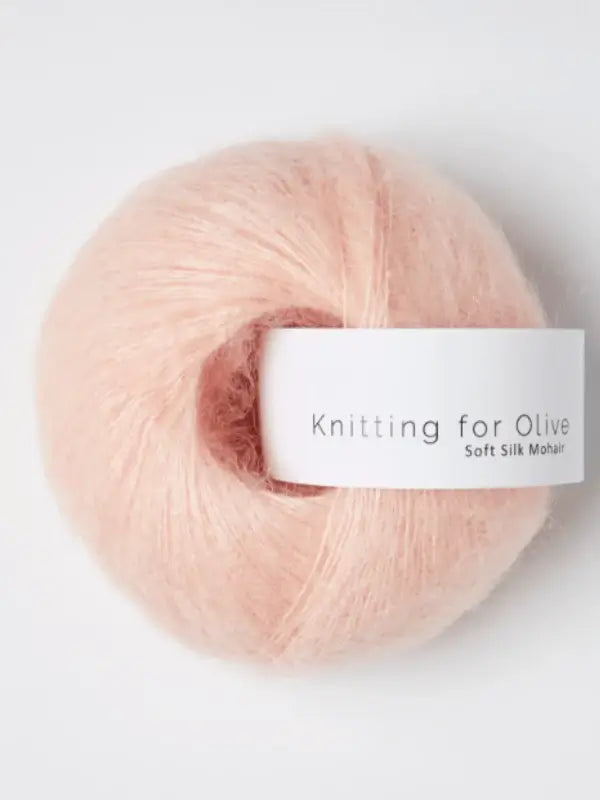 A soft, light pink ball of Knitting for Olive Soft Silk Mohair yarn, made from luxurious kid mohair fibers and wrapped with a white band around the skein.