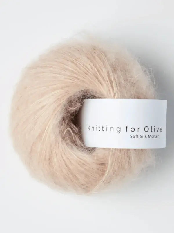 A skein of Knitting for Olive Soft Silk Mohair yarn in soft beige, featuring a white label, is shown against a plain white background.