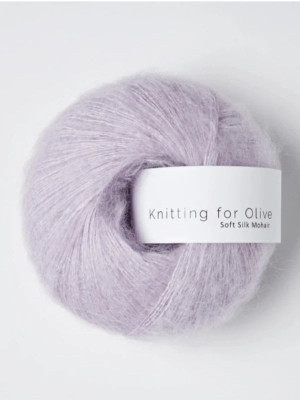 A ball of pale lavender Knitting for Olive Soft Silk Mohair yarn rests against a light background. Composed of soft, fuzzy Kid Mohair and silk, it boasts a delicate, slightly lustrous texture. Crafted in accordance with the Responsible Mohair Standard, this silkki lanka guarantees both high quality and ethical sourcing.