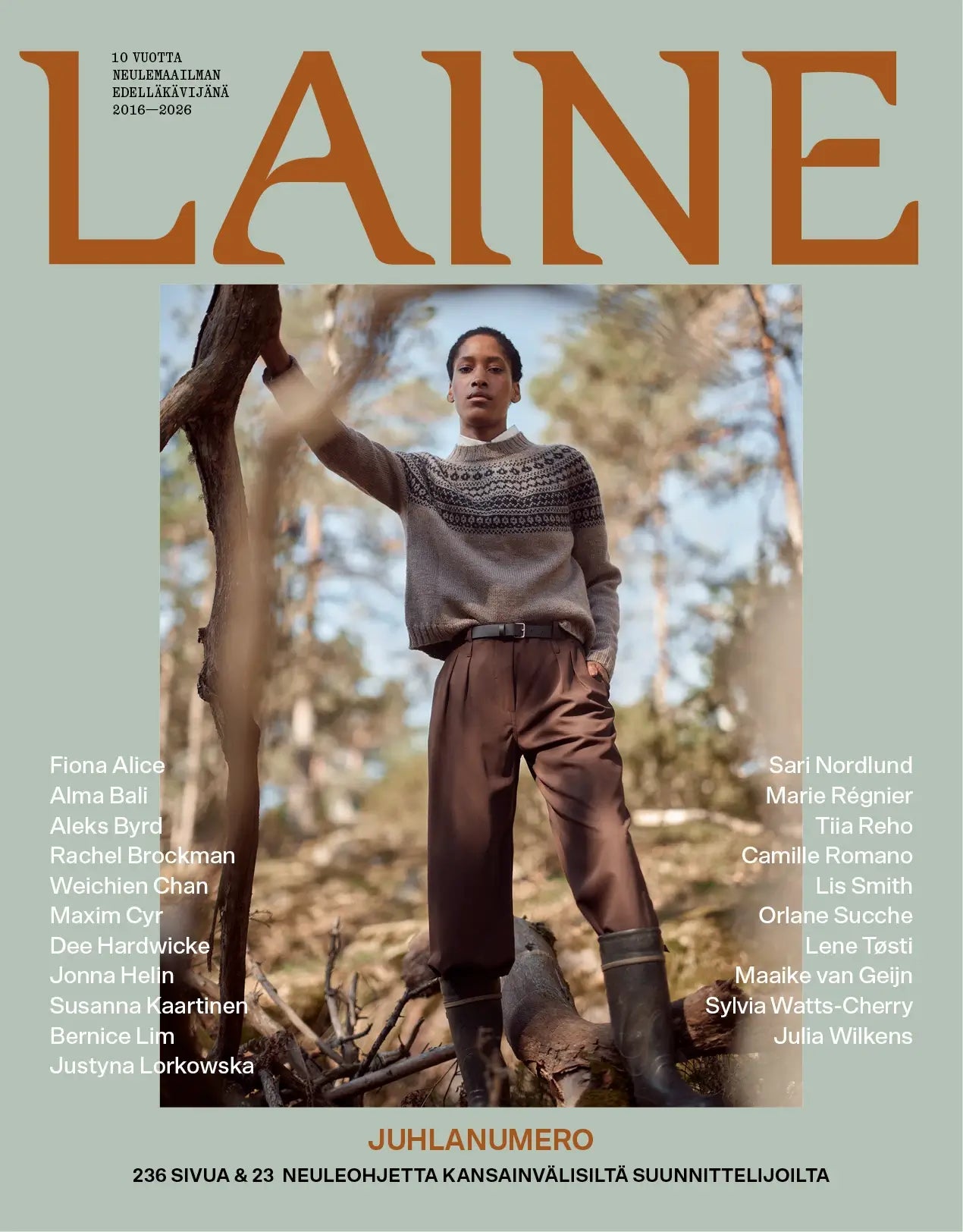 A woman stands in a forest wearing a brown patterned sweater and dark high-waisted pants. The Laine Juhlanumero - ENNAKKO cover lists designers’ names and Finnish text, celebrating 10 years of nordic style.