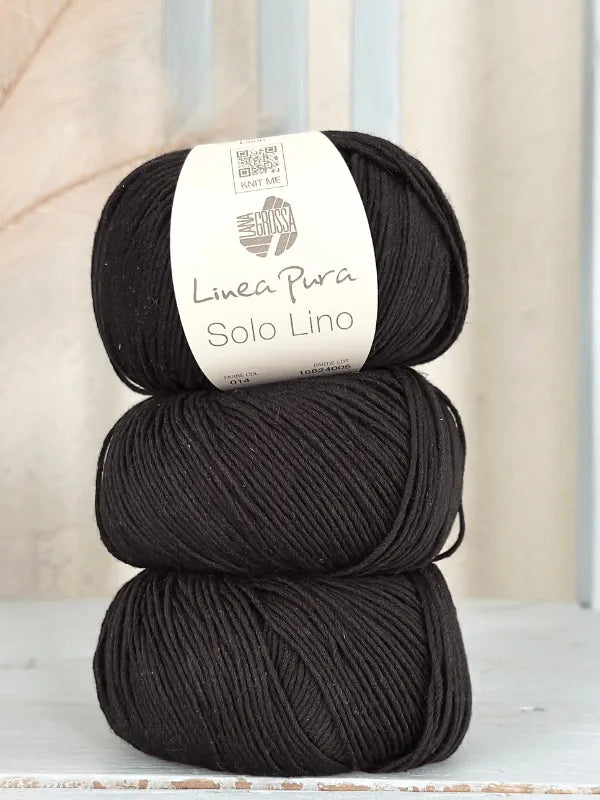 Three skeins of black Lana Grossa Solo Lino, a soft vegan yarn, are stacked with the branded label visible on the top. The background is light-colored and softly blurred.