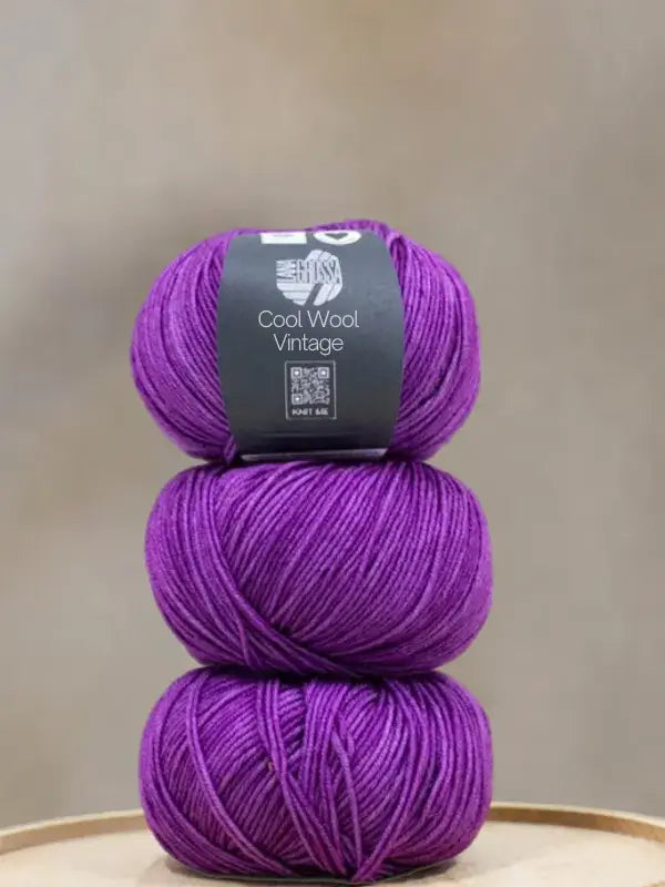 Three balls of Lana Grossa Cool wool vintage purple yarn stacked vertically.