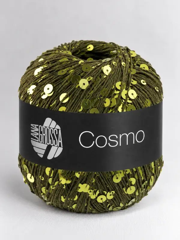 A ball of olive green Lana Grossa Cosmo yarn interspersed with small, shiny gold sequins, wrapped in a black paper label.