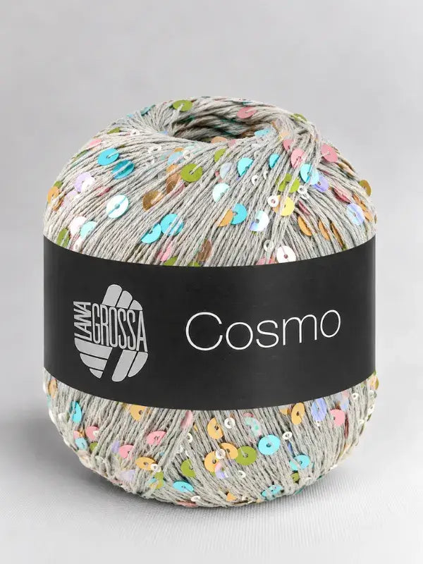 A ball of light gray Lana Grossa Cosmo yarn flecked with multicolored sequins, wrapped in a black paper band.