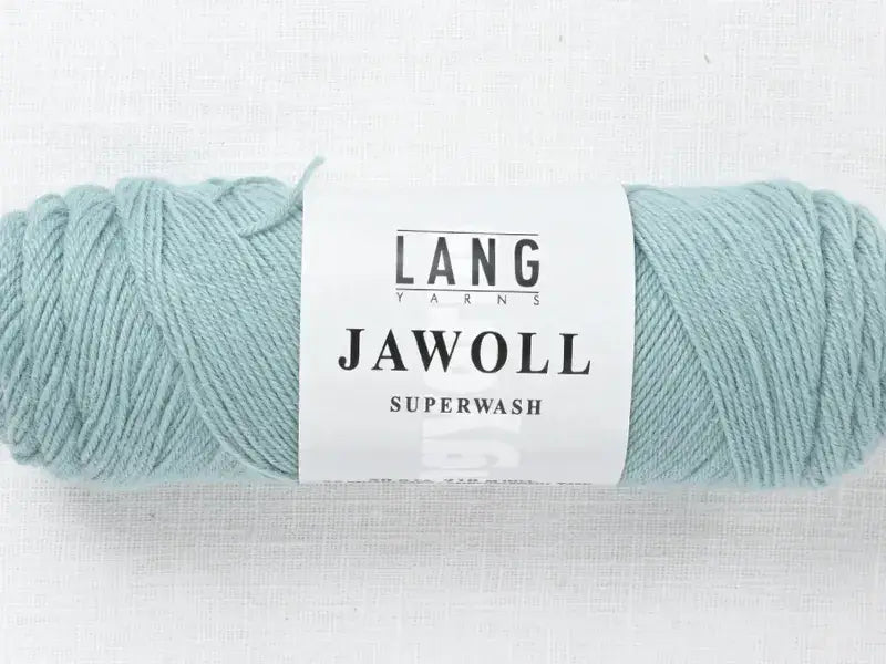 A skein of pale mint green Lang Yarns Jawoll with a product label.