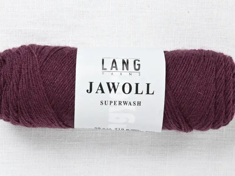 A skein of deep purple Lang Yarns Jawoll with a white label.