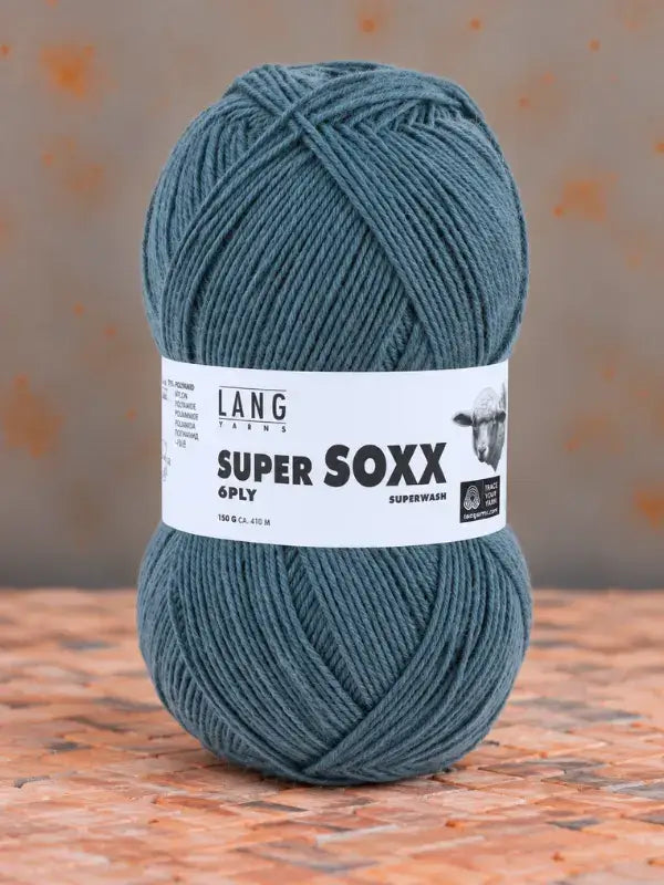A ball of teal Lang Yarns Super Soxx 6 ply – kestävä sukkalanka villasta with a product label featuring text and an illustration of a sheep.