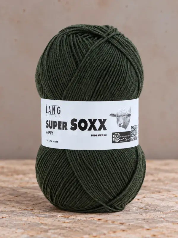 A ball of forest green Lang Yarns Super Soxx 6 ply – kestävä sukkalanka villasta yarn with a product label featuring text, a sheep illustration, and a QR code.