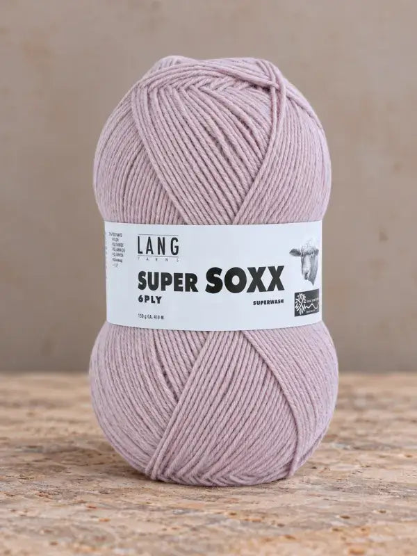 A ball of dusty pink Lang Yarns Super Soxx 6 ply – kestävä sukkalanka villasta with a product label.