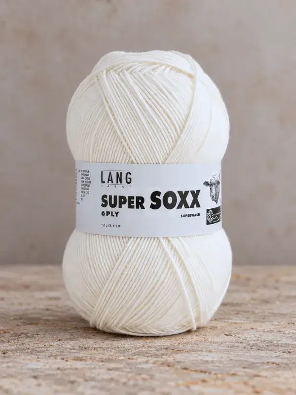 A ball of solid white Lang Yarns Super Soxx 6 ply – kestävä sukkalanka villasta wool yarn with a product label around the center.