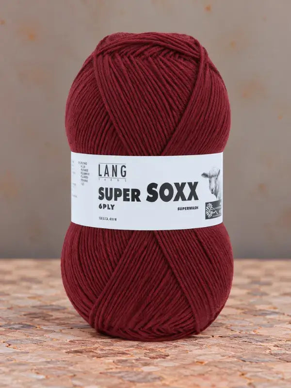 A ball of deep red Lang Yarns Super Soxx 6 ply – kestävä sukkalanka villasta yarn wrapped in a matching label.