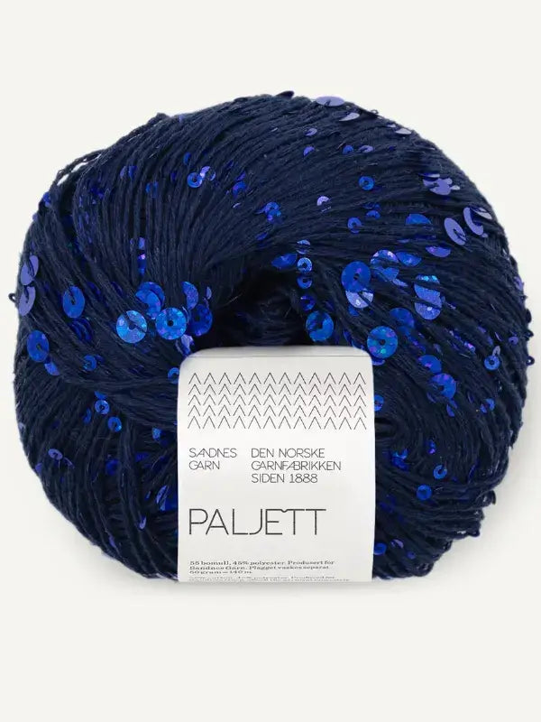 A skein of Sandnes Garn Paljett, a dark blue yarn covered in shimmering sequins with a product label centered on the front.