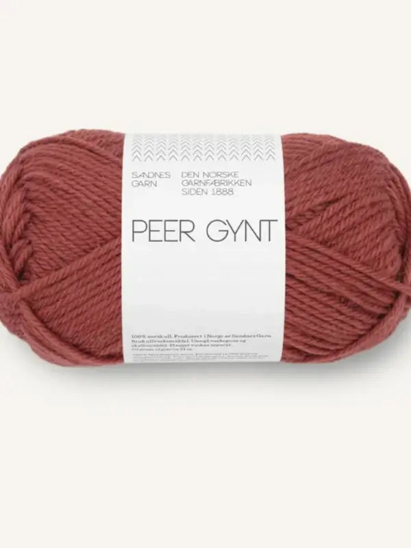 A skein of reddish-brown Sandnes Garn Peer Gynt norjalainen villa yarn, featuring a white label with Norwegian text.