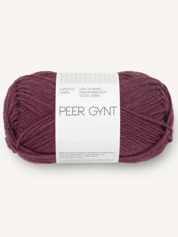 A skein of burgundy Sandnes Garn Peer Gynt yarn with a white label wrapped around it, displaying gray text and patterns. This Norwegian wool yarn is renowned for its quality and durability.