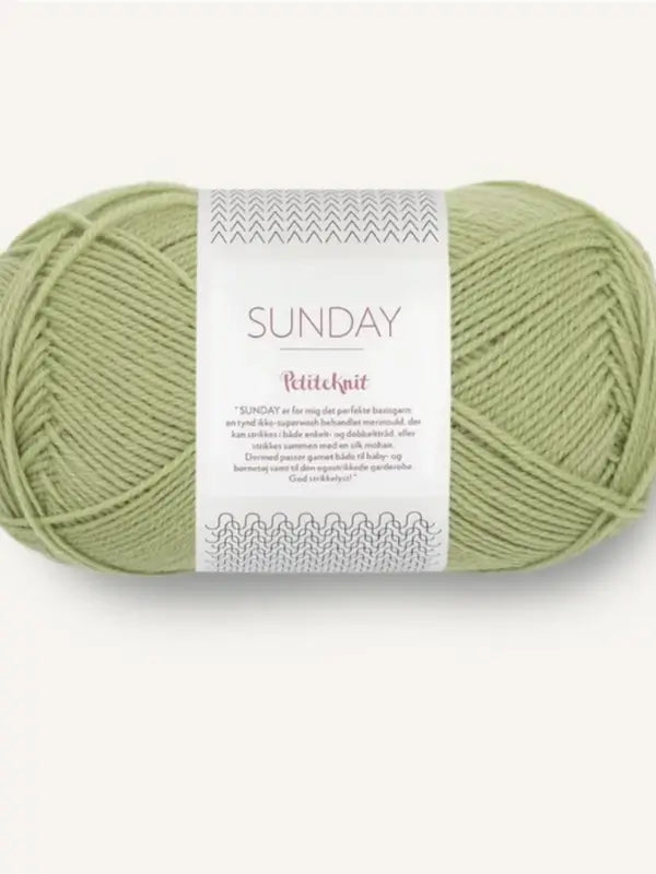 A skein of light green, fingering-weight merino wool yarn labeled Sandnes Garn Sunday with knitting pattern graphics on a white label, placed against a plain light background. This yarn is also mulesing-free, ensuring ethical quality for your projects.