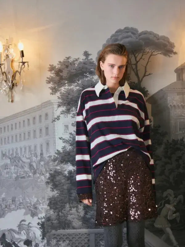 A person wears a long-sleeved navy, red, and white striped rugby shirt with a white collar paired with a dark brown sequined Sandnes Garn Vea skirt – neulesetti Paljett.