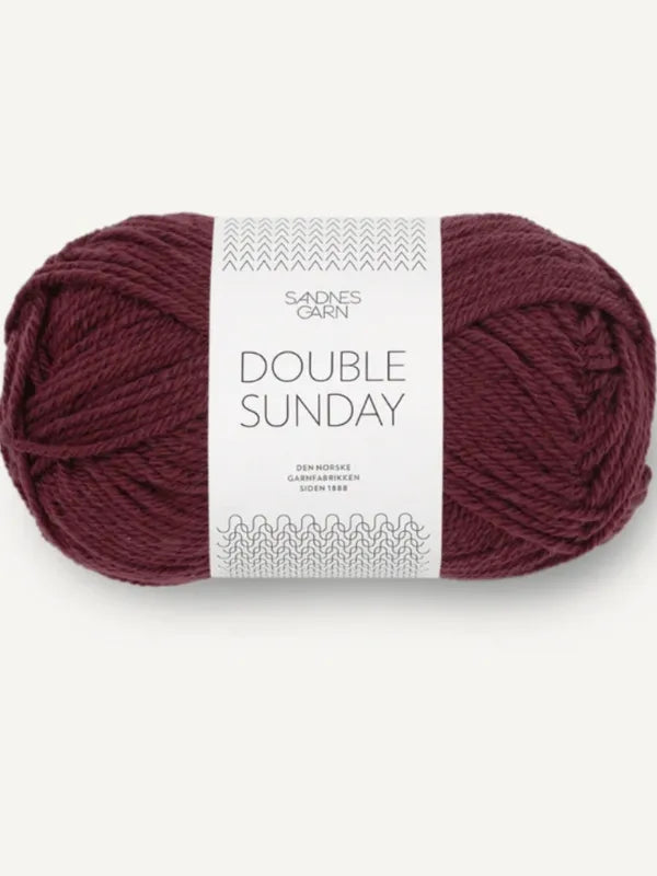 A skein of deep burgundy yarn labeled Sandnes Garn Double Sunday, accompanied by the PetiteKnit Scarlet Sweater pattern in Finnish (neuleohje suomi), with white packaging displaying the brand and product names.