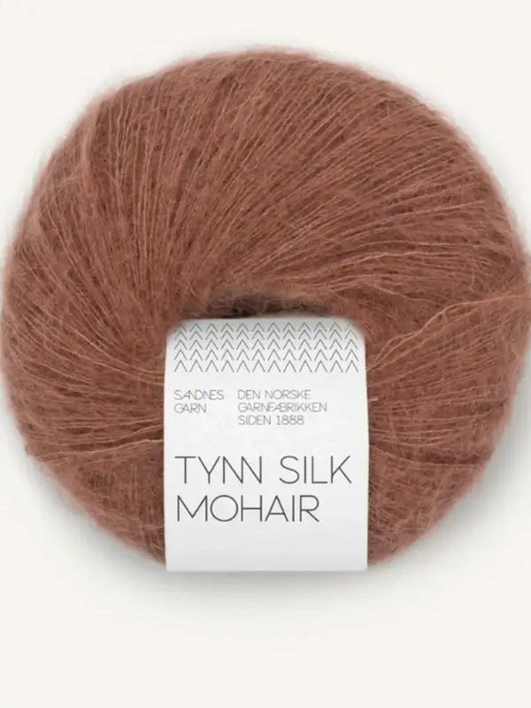 A soft, brown ball of mohair yarn labeled Sandnes Garn Tynn Silk Mohair, featuring additional Norwegian text on the white band around the skein. This luxurious Tynn Silk Mohair yarn is perfect for delicate and elegant knitting projects.