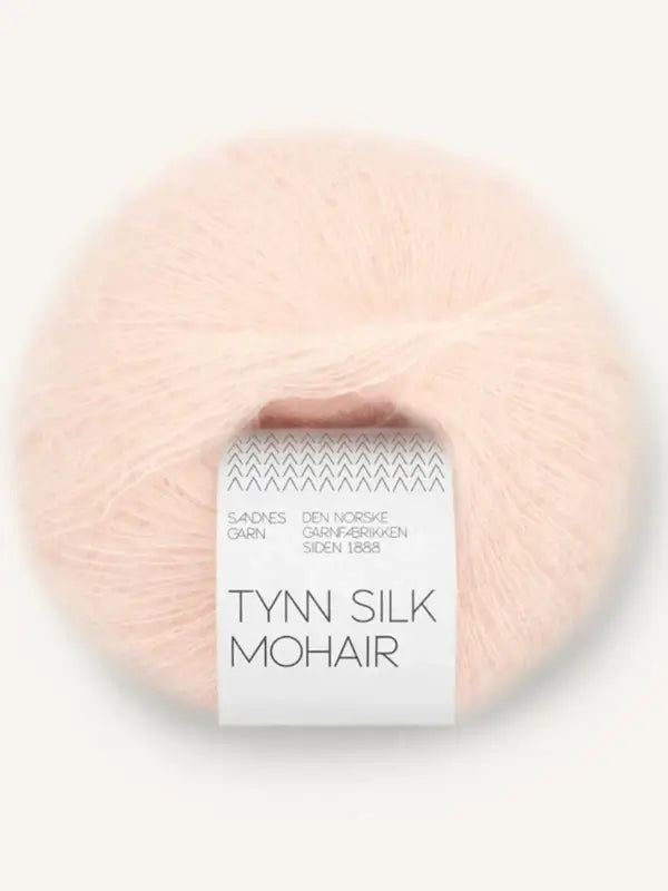 A ball of pale pink yarn labeled Sandnes Garn Tynn Silk Mohair—a luxurious silk-mohair blend produced by the Norwegian yarn company Sandnes Garn, established in 1888.
