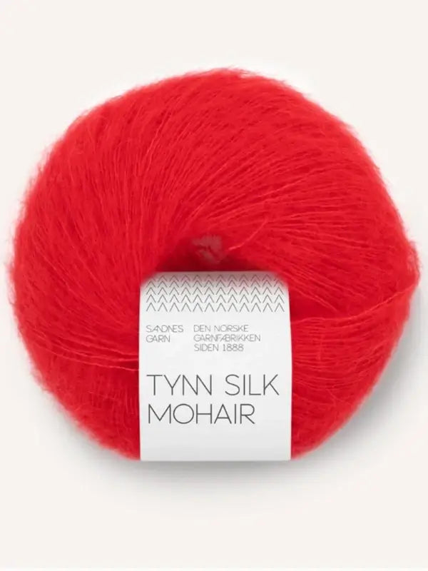 A ball of vibrant red Sandnes Garn Tynn Silk Mohair yarn, featuring a white and gray label around it, is displayed against a light background.