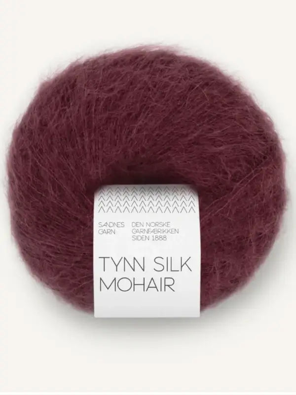 A ball of Sandnes Garn Tynn Silk Mohair yarn in burgundy, featuring white and gray packaging, displayed on a light background.