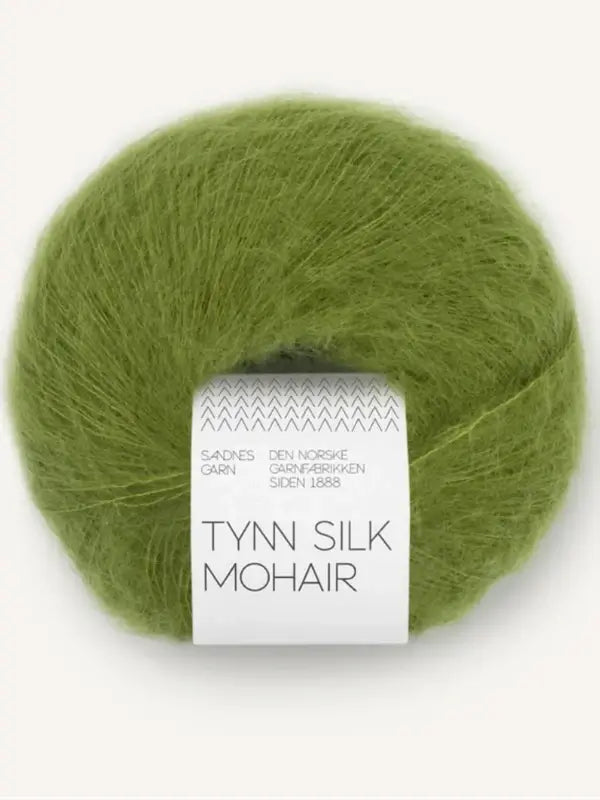 A ball of Sandnes Garn Tynn Silk Mohair green mohair yarn featuring a white label with “Tynn Silk Mohair” as the main title and additional text in smaller letters above, showcasing this luxurious silkki-mohairlanka blend.