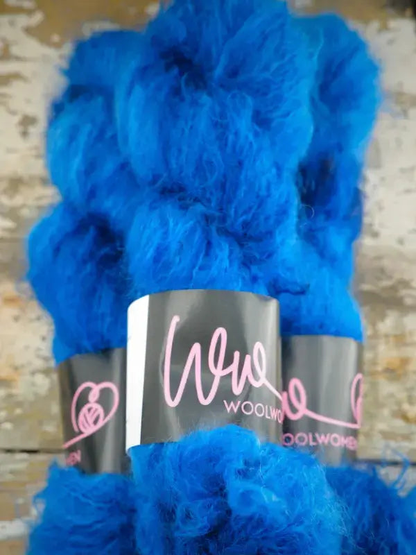 Two skeins of bright blue WoolWomen Fluff Mohair yarn with black labels.