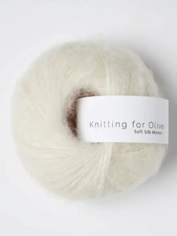 A skein of Knitting for Olive Soft Silk Mohair yarn—soft, airy, and off-white in color—crafted from fine Kid mohair fibers and luxurious silkki, is displayed against a simple background.